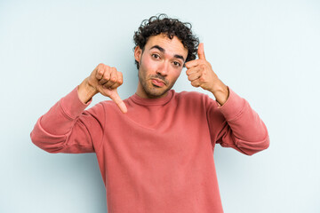 Young caucasian man isolated on blue background showing thumbs up and thumbs down, difficult choose...