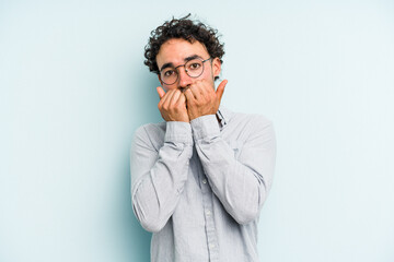 Young caucasian man isolated on blue background biting fingernails, nervous and very anxious.