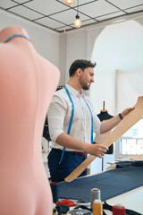 Obraz premium Man couturier works with pattern in a sewing workshop
