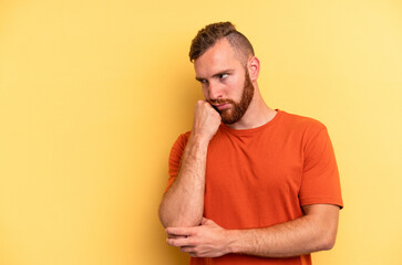 Young caucasian man isolated on yellow background who feels sad and pensive, looking at copy space.