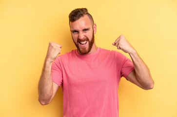 Fototapeta premium Young caucasian man isolated on yellow background cheering carefree and excited. Victory concept.