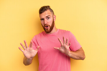 Young caucasian man isolated on yellow background rejecting someone showing a gesture of disgust.