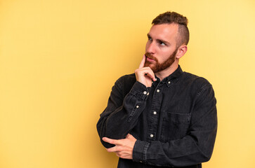 Fototapeta premium Young caucasian man isolated on yellow background relaxed thinking about something looking at a copy space.