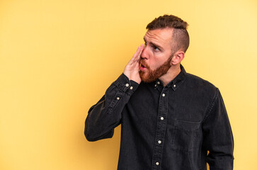 Obraz premium Young caucasian man isolated on yellow background is saying a secret hot braking news and looking aside