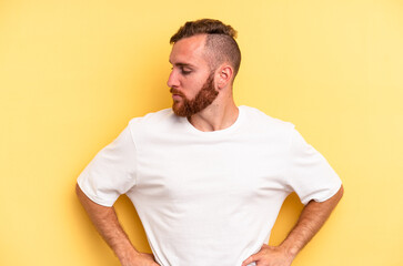 Young caucasian man isolated on yellow background dreaming of achieving goals and purposes