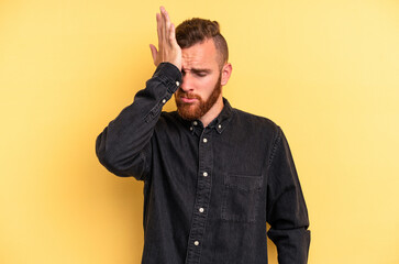 Young caucasian man isolated on yellow background forgetting something, slapping forehead with palm...