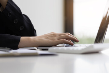 Close-up of a business woman working on a laptop in the office typing on a keyboard.