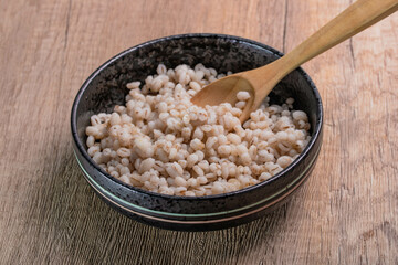 Job's tears boiled in a cup with a wooden spoon. Healthy whole grains.