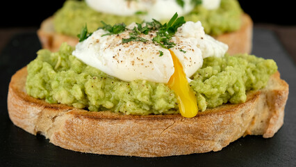 poached egg with runny egg yolk over bread toast with mashed avocado spread