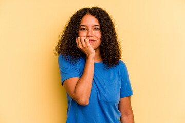 Young Brazilian woman isolated on yellow background biting fingernails, nervous and very anxious.
