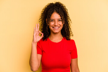 Young Brazilian woman isolated on yellow background cheerful and confident showing ok gesture.