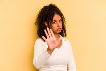 Young Brazilian woman isolated on yellow background rejecting someone showing a gesture of disgust.