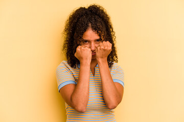 Young Brazilian woman isolated on yellow background throwing a punch, anger, fighting due to an...