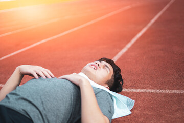 Exhausted man resting after jogging in the stadium during day.