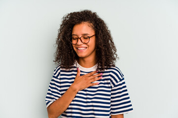 Young Brazilian woman isolated on blue background laughing keeping hands on heart, concept of happiness.