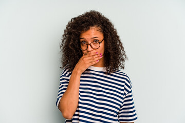 Young Brazilian woman isolated on blue background covering mouth with hands looking worried.