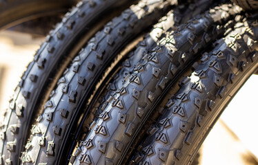 stack of black replacement bike tires for sale,outside sunny summer day.outdoor market.mountain bike tires with different rubber structure.high-volume, lightweight true racing bicycle tire