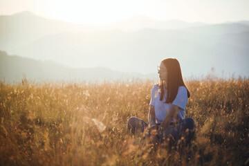 Naklejka na ściany i meble Beautiful Teen Girl sitting in Mountain Golden Field