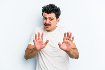 Young caucasian man isolated on blue background rejecting someone showing a gesture of disgust.