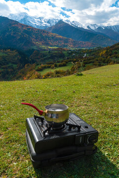 Portable tourist gas stove with a bucket of water and chicken eggs on the background of the beautiful autumn Caucasus mountains. Camp kitchen and tea making facilities. Vertical photo