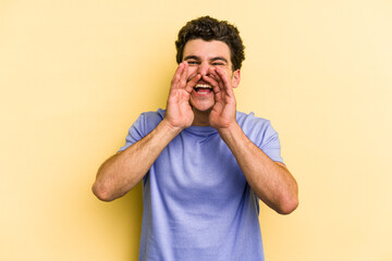 Young caucasian man isolated on yellow background saying a gossip, pointing to side reporting something.