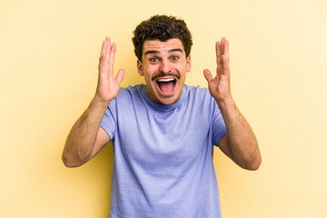 Young caucasian man isolated on yellow background receiving a pleasant surprise, excited and raising hands.