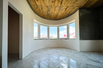 Empty room with putty white arch wall and tiles floor.