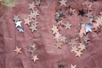 Top view of the silver glittering stars scattered on a brown background. Dreaming, fairy tale, magic, miracle concept