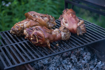 Several traditional Bavarian German roasted pork knuckles slowly cooked at rotating broiling rack grill spit, close up, low angle side view. barbecue. the concept of cooking on an open fire.