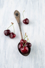 Blurred image of cherries in a spoon on a light table.