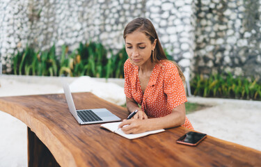 Intelligent female copywriter writing content ideas while creating text publication about digital...