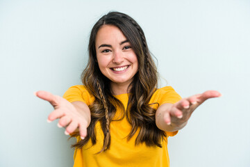 Young caucasian woman isolated on blue background showing a welcome expression.