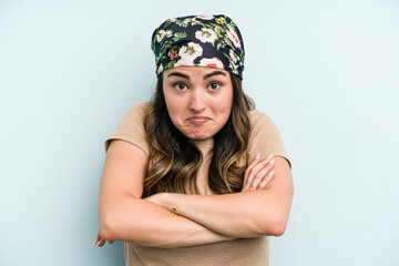 Young caucasian woman isolated on blue background shrugs shoulders and open eyes confused.