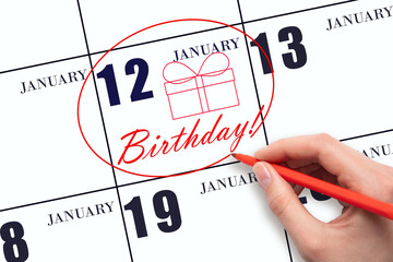 The hand circles the date on the calendar 12 January, draws a gift box and writes the text Birthday. Holiday.