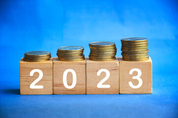 New year 2023 text on wooden blocks with gold coins on top.