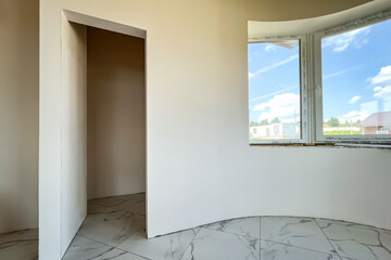 Empty room with putty white arch wall and tiles floor.