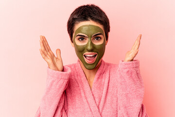 Young caucasian woman wearing a face mask isolated on pink background receiving a pleasant surprise, excited and raising hands.