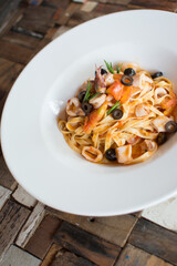 Pasta with seafood. Prawns, squid and octopus. white plate olives.


