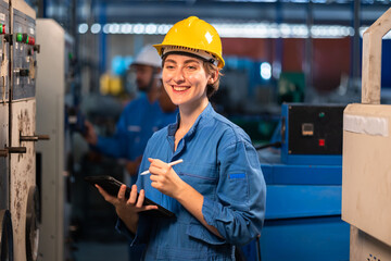 Young female worker  in protective uniform operating machine at factory Industrial.People working...