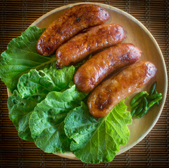 Isaan sausage or Thai Northeastern sausage , pork and rice sausages (Sai Krok Isan ) on wood plate with cabbage, and chilli - obrazy, fototapety, plakaty