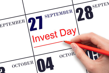 Hand drawing red line and writing the text Invest Day on calendar date September 27. Business and...