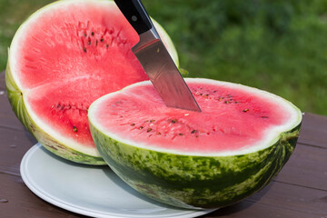 The watermelon was cut in half and stuck with a knife. - 515006666