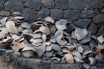Broken pieces of black clay earthen pots. Black rock stone wall background, pattern or texture