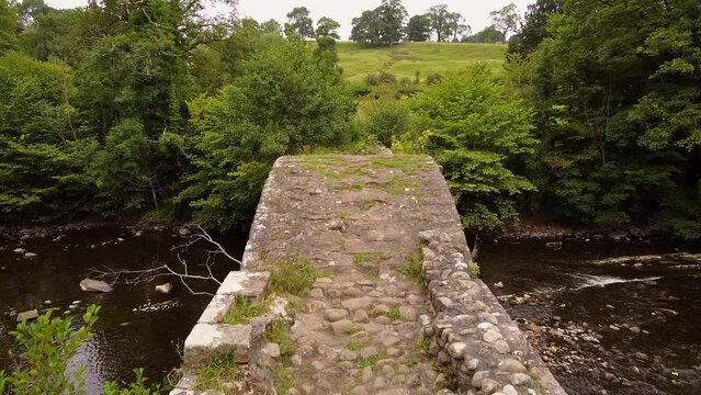 aerial view of cobbled pathway over cromwells bridge over rolling stream