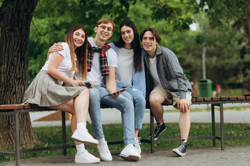 Fototapeta premium Carefree students using gadget outdoors