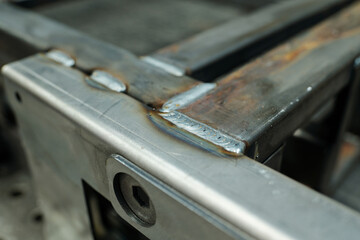 Close-up of metallic welded parts of industrial machine or workbench which is workplace of welder...