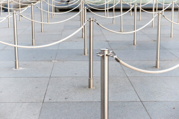 Path with line of silver metal poles in front of ticket office with no people
