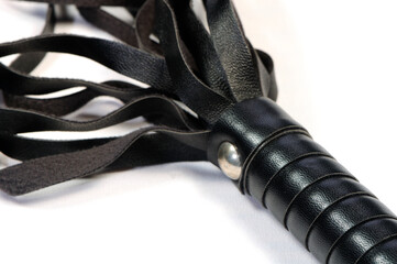 A black leather whip on a white background used in role playing used in sadomasochism and...