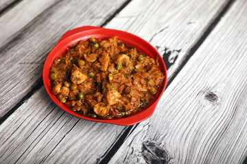 Indian traditional homemade spicy mushroom curry in a bowl on wooden table