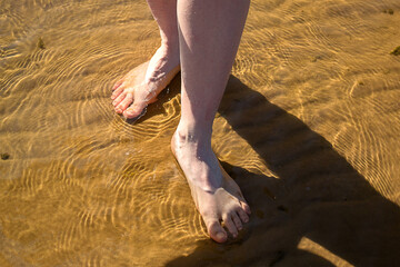 Legs of a girl close-up. Barefoot on sand and water. Legs of a woman girl goes along the coast of the sea. lifestyle, vacation, relaxation